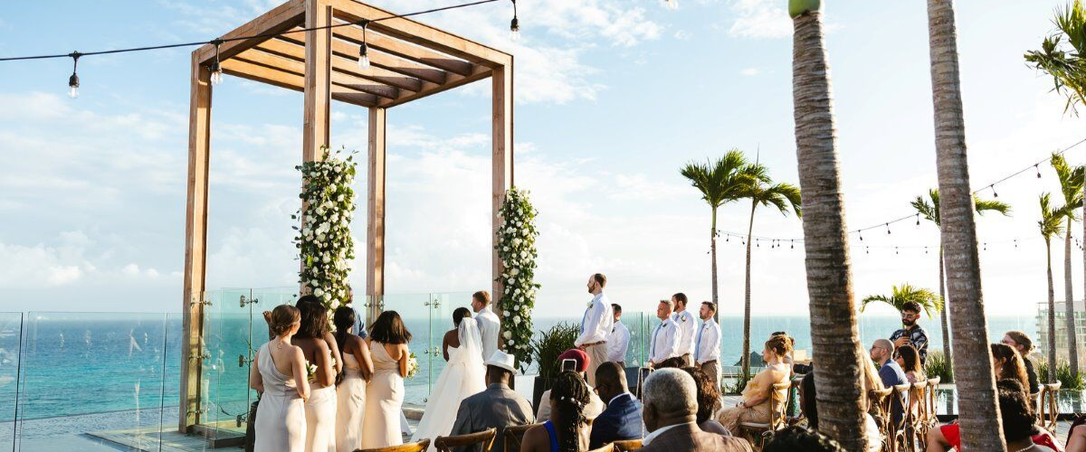 Destination wedding, beach wedding, bride and groom, wedding party, and guests overlooking ocean, wedding ceremony