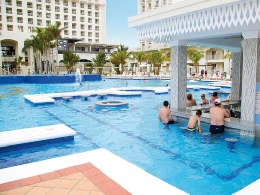 Tourists at the swim up pool bar in Hotel Riu palace in Aruba. Plan your trip with D'Amico Travel.