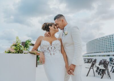 couple kissing at their ceremony at a destination wedding. both are holding hands and wearing white.