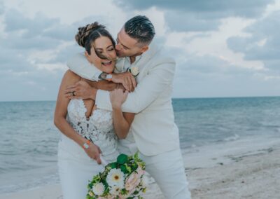 groom kissing his bride on the beach at their destination wedding.