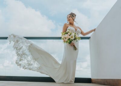bride wearing gown and holding a bouquet, posing at her hotel balcony for her destination wedding in paradise.