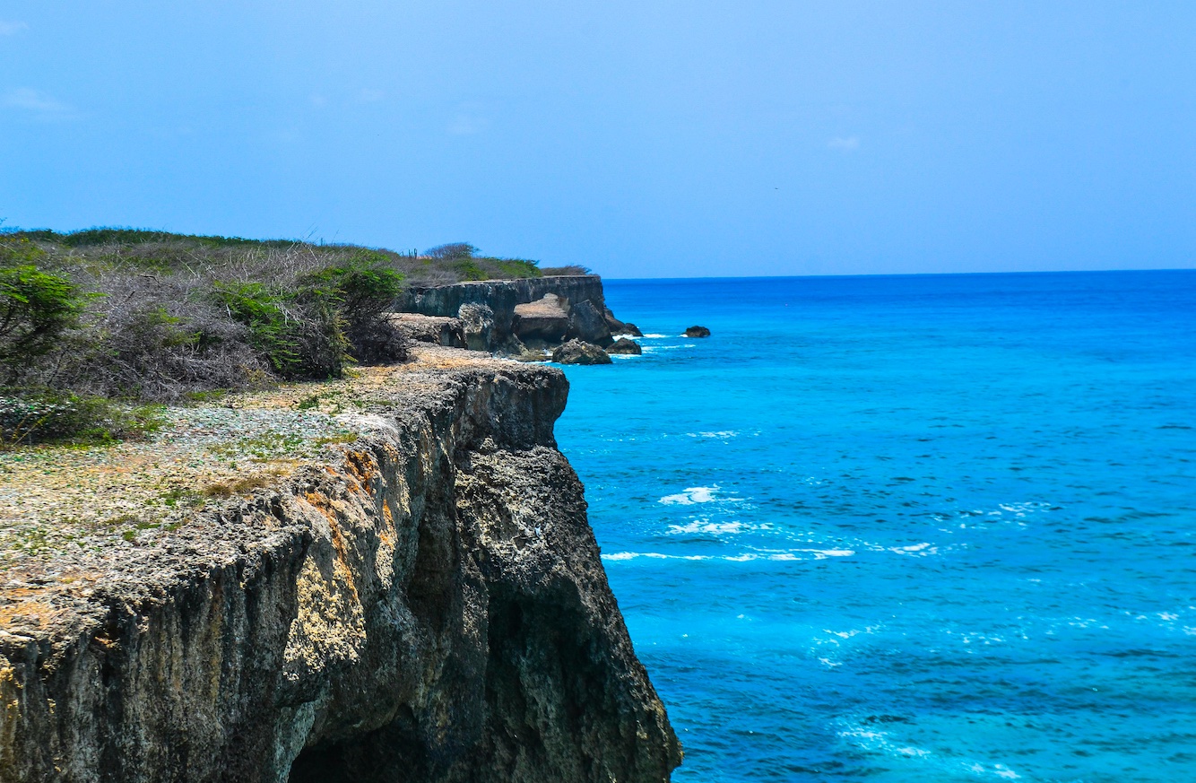 Cliffside beach Curacao view of a cliffside beach in Curacao, blue seas and rocky cliffs on a sunny day.